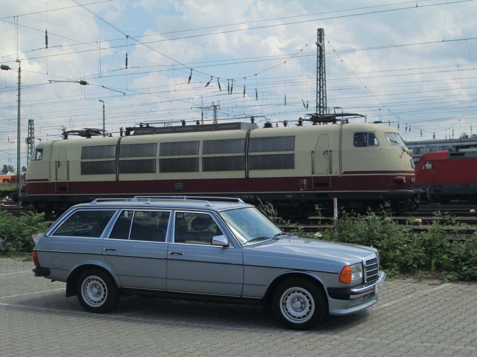 Silbernes W123 T-Modell vor einer historischen Schnellzuglokomotive